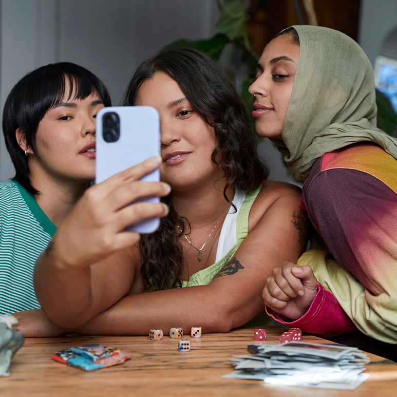 Three women leaning in toward each other for a group selfie.