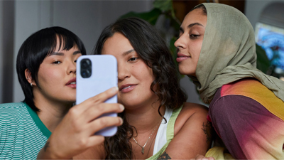 Three women leaning in toward each other for a group selfie.