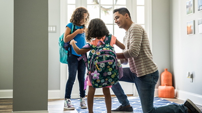 Father helping children with their backpacks.